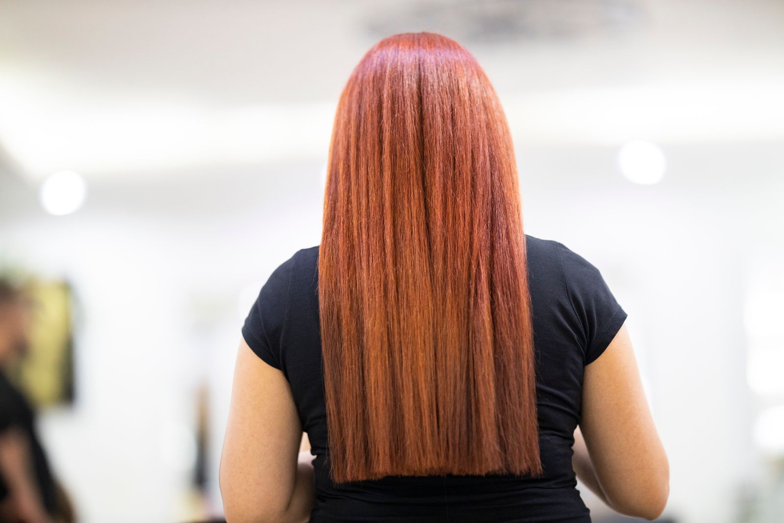Păr lung arămiu, drept și lucios, fotografiat din spate în salon