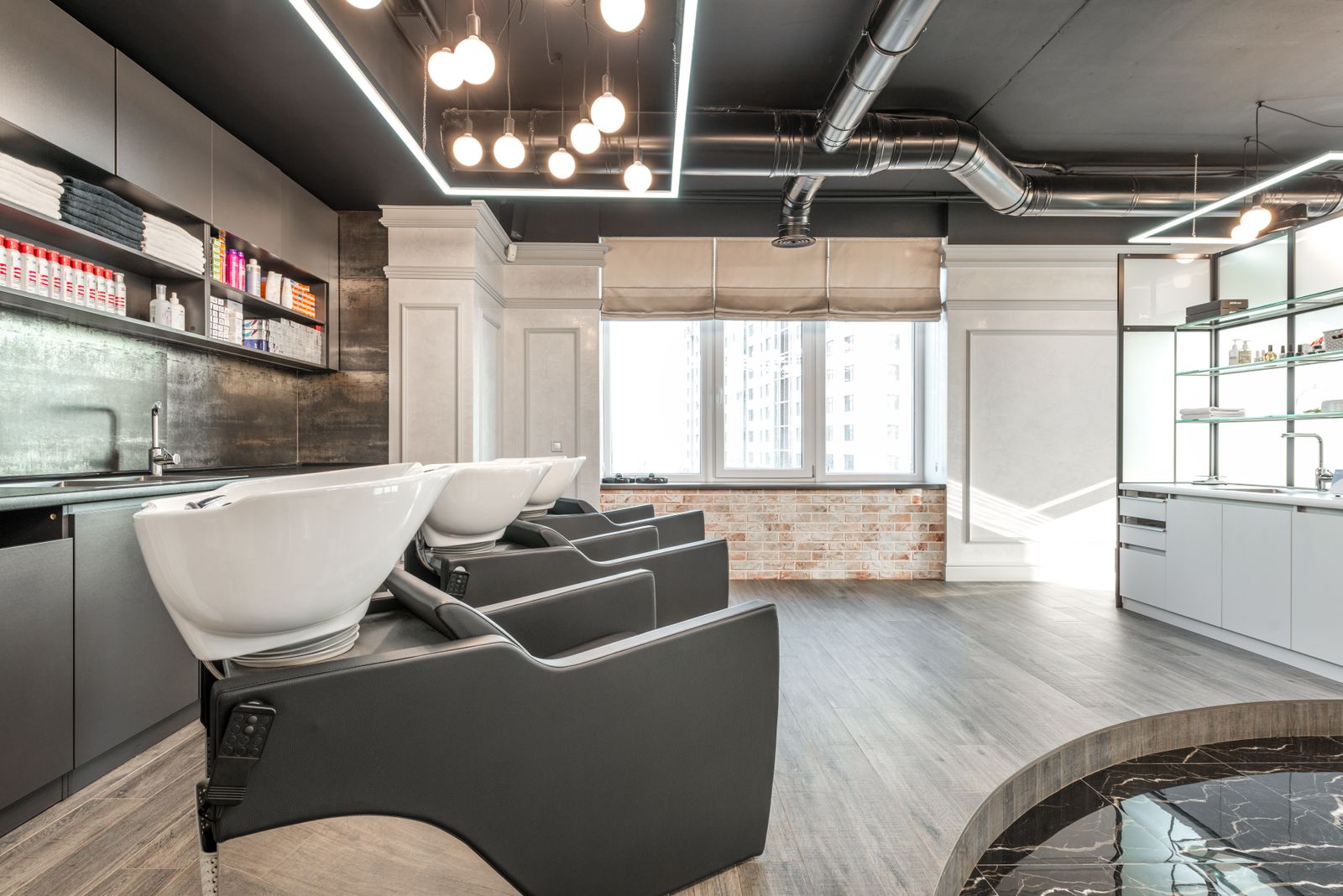 Interiorul salonului Studio Nuanță, zona de spălat cu tavan negru și lumini calde